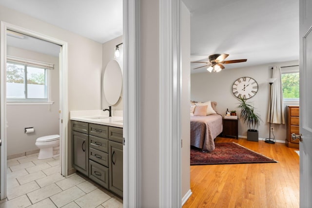 ensuite bathroom featuring a ceiling fan, plenty of natural light, vanity, and toilet