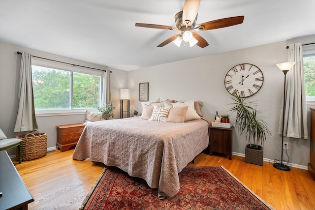 bedroom featuring multiple windows, wood finished floors, baseboards, and ceiling fan