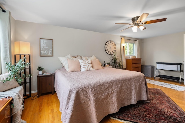 bedroom with light wood-type flooring, a ceiling fan, and baseboards