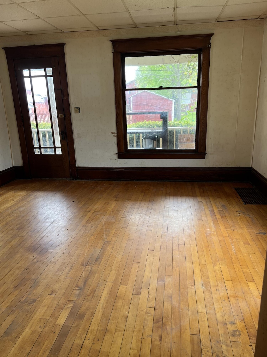 311 N Washington St, Charlotte, MI 48813 - empty room featuring a drop ceiling, hardwood / wood-style floors, and baseboards