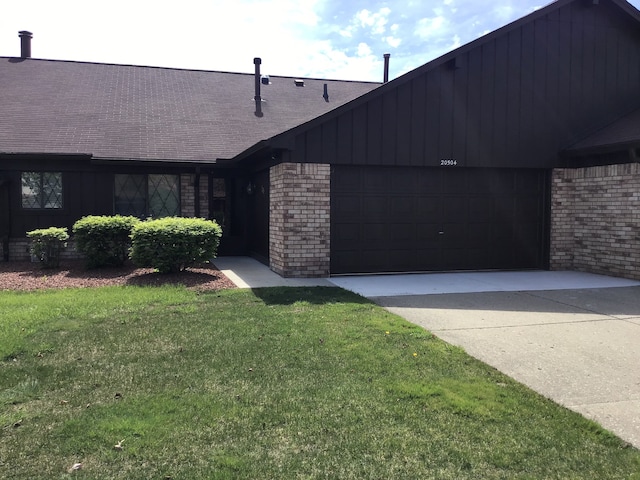 view of front of home with brick siding, a garage, driveway, and a front yard