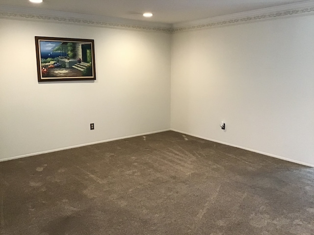 empty room with dark colored carpet, ornamental molding, baseboards, and recessed lighting
