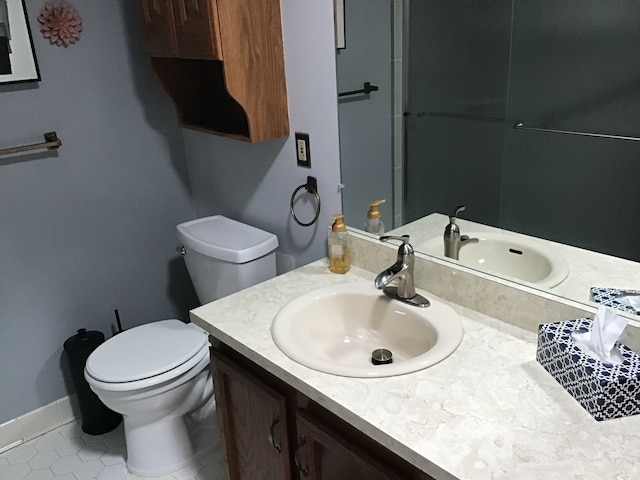 bathroom featuring toilet, vanity, tile patterned floors, and baseboards