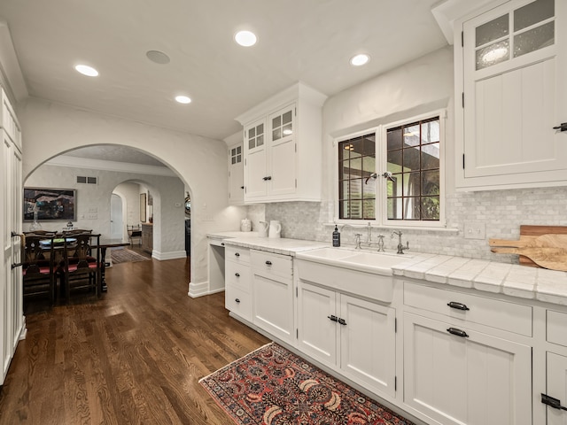 404 Linden Rd, Birmingham, MI 48009 - kitchen with arched walkways, light countertops, white cabinets, recessed lighting, and glass insert cabinets
