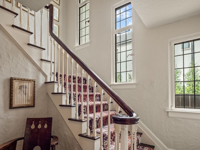 404 Linden Rd, Birmingham, MI 48009 - staircase with healthy amount of natural light, a textured wall, baseboards, and a high ceiling