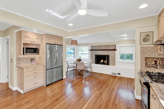950 W Lincoln St, Birmingham, MI 48009 - kitchen with appliances with stainless steel finishes, a large fireplace, a ceiling fan, backsplash, and light wood-type flooring