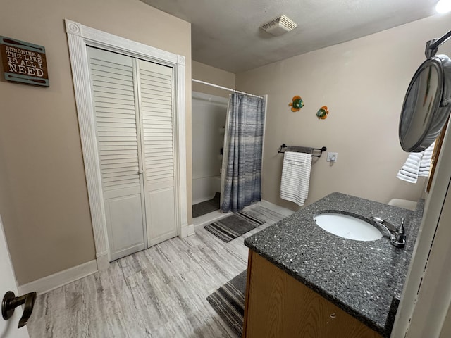 11619 Scott Park Rd, Delton, MI 49046 - full bathroom featuring wood finished floors, a shower with shower curtain, vanity, and baseboards