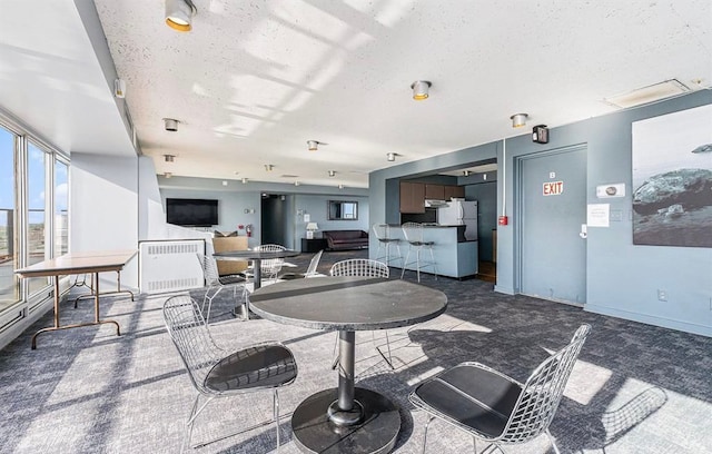 8200 E Jefferson Ave Unit 59/602, Detroit, MI 48214 - dining area featuring a textured ceiling, dark colored carpet, and baseboards