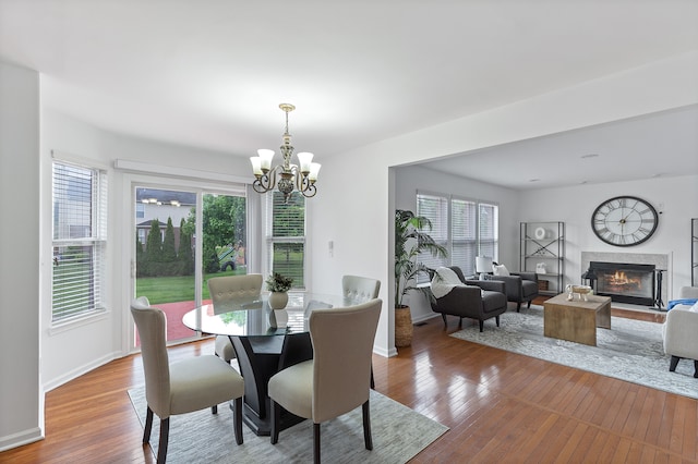 14190 Elmhurst Dr, Sterling Heights, MI 48313 - dining area with a chandelier, wood-type flooring, a premium fireplace, and baseboards