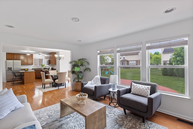 14190 Elmhurst Dr, Sterling Heights, MI 48313 - living room with a chandelier, baseboards, and light wood-style flooring