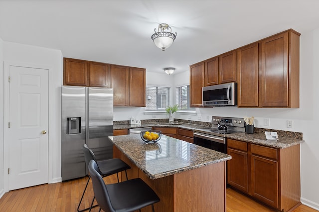 14190 Elmhurst Dr, Sterling Heights, MI 48313 - kitchen with appliances with stainless steel finishes, a breakfast bar, light wood-style floors, dark stone counters, and a center island