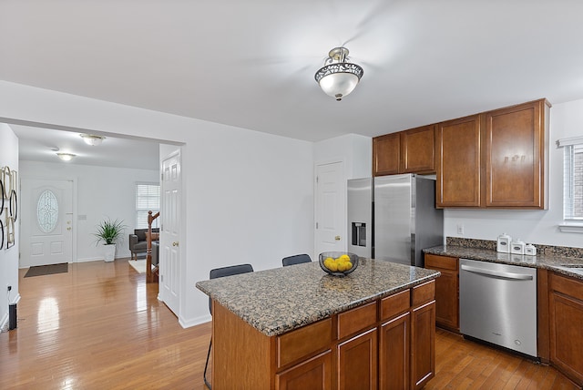 14190 Elmhurst Dr, Sterling Heights, MI 48313 - kitchen featuring stainless steel appliances, light wood-style flooring, dark stone counters, a kitchen island, and brown cabinets