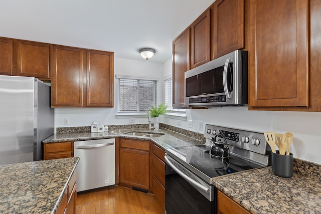 14190 Elmhurst Dr, Sterling Heights, MI 48313 - kitchen with stainless steel appliances, a sink, dark stone counters, light wood-style floors, and brown cabinets