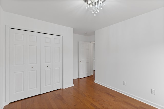 14190 Elmhurst Dr, Sterling Heights, MI 48313 - unfurnished bedroom with baseboards, wood finished floors, a closet, and a chandelier