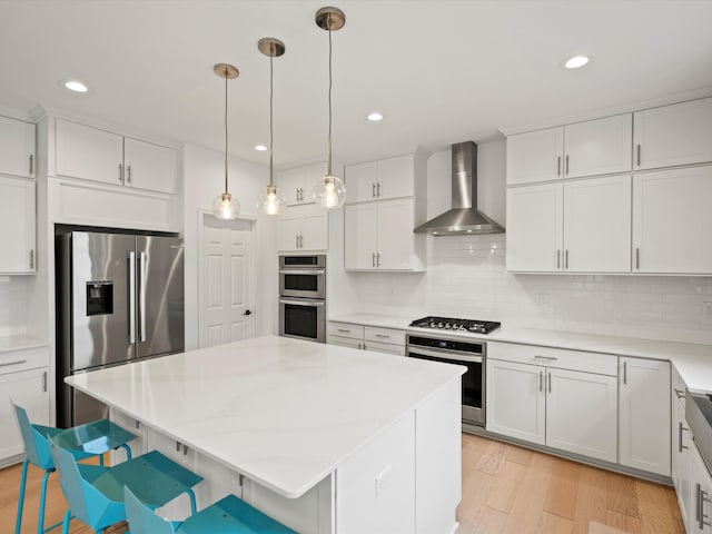 4321 Sparrow St, Ann Arbor, MI 48103 - kitchen featuring wall chimney range hood, stainless steel appliances, tasteful backsplash, a kitchen island, and white cabinets