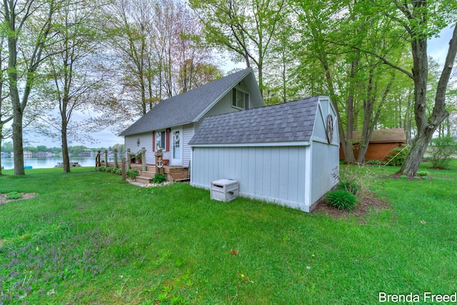 2551 Mayo Dr, Fremont, MI 49412 - view of side of home with roof with shingles, a water view, a lawn, an outbuilding, and a storage unit