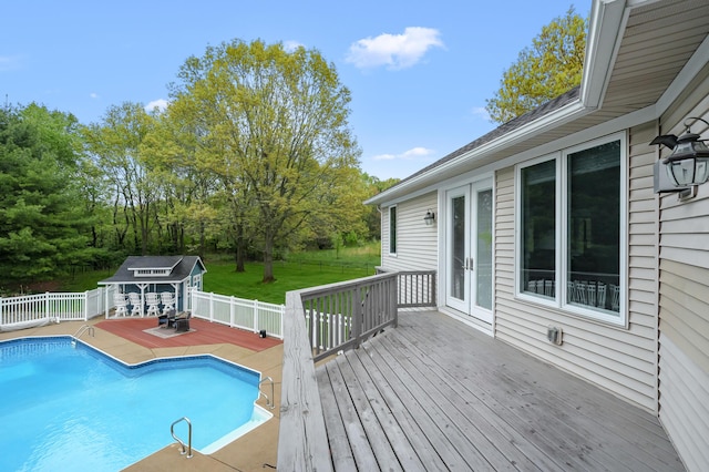 view of swimming pool with a deck, french doors, and an outbuilding
