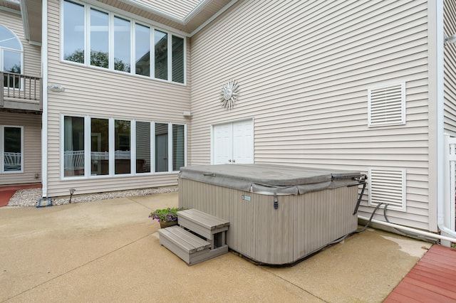 back of property featuring a hot tub and a patio