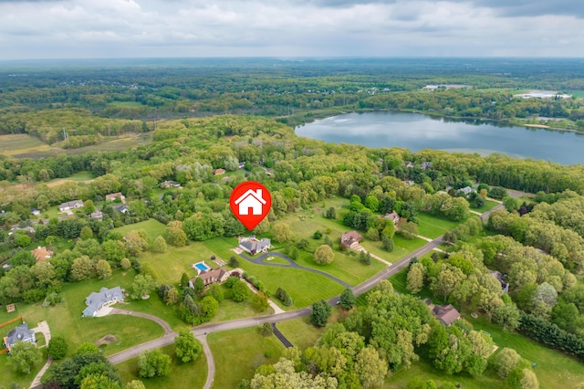 drone / aerial view of a nearby body of water and a heavily wooded area