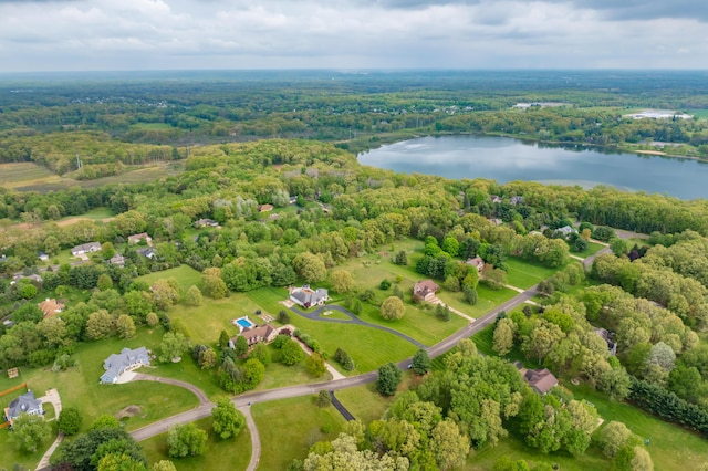 drone / aerial view of a nearby body of water and a heavily wooded area