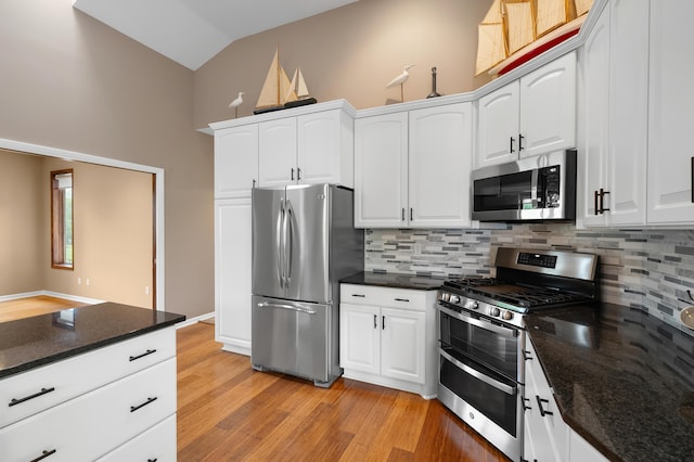 kitchen featuring appliances with stainless steel finishes, backsplash, light wood-style floors, white cabinets, and high vaulted ceiling
