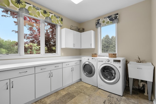 washroom with cabinet space, independent washer and dryer, and stone finish floors