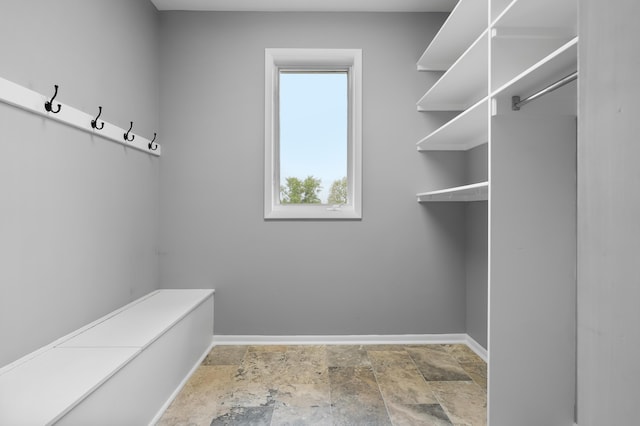 walk in closet with stone tile flooring