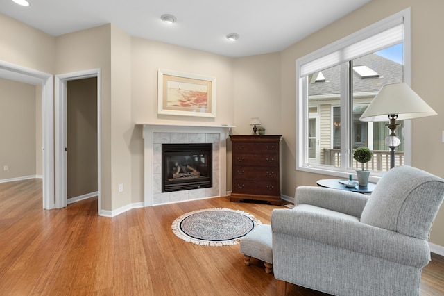 living area with a tile fireplace, wood finished floors, baseboards, and recessed lighting