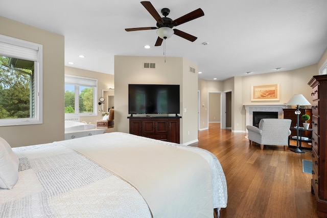 bedroom with wood finished floors, a fireplace, recessed lighting, baseboards, and a ceiling fan
