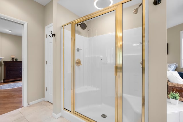 bathroom with ensuite bathroom, a stall shower, tile patterned floors, and baseboards