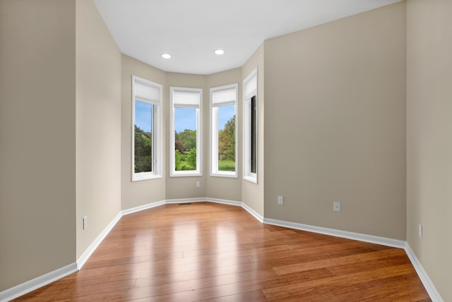 unfurnished room with wood finished floors, baseboards, and recessed lighting