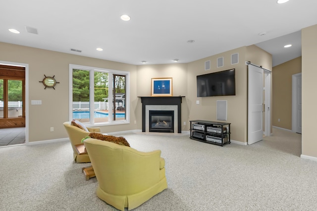carpeted living room with baseboards, a premium fireplace, recessed lighting, and a barn door