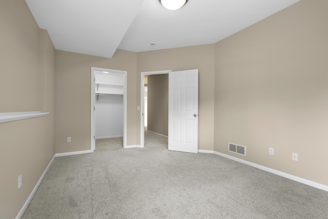unfurnished bedroom featuring carpet, baseboards, a walk in closet, and a closet