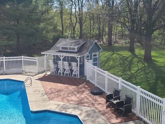 view of swimming pool with a deck, an outbuilding, a storage structure, and a lawn