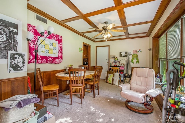 dining space with coffered ceiling, carpet floors, ceiling fan, wainscoting, and wood walls