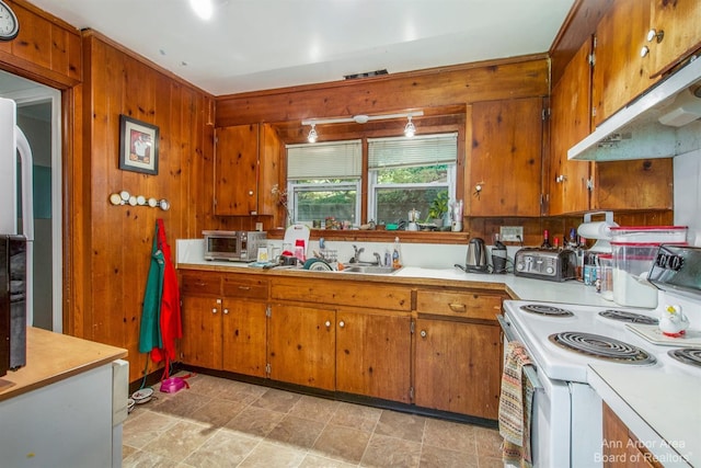 kitchen featuring white electric stove, brown cabinets, light countertops, under cabinet range hood, and wood walls