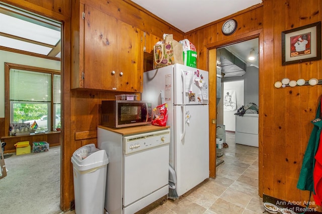 kitchen featuring white appliances, wooden walls, washer / dryer, and brown cabinets