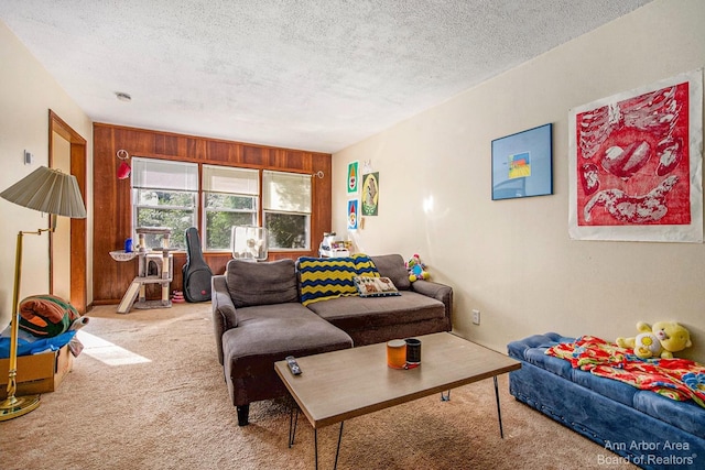 living area with carpet flooring, a textured ceiling, and wood walls