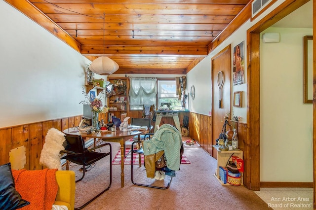 carpeted dining room with wooden ceiling, wood walls, and wainscoting