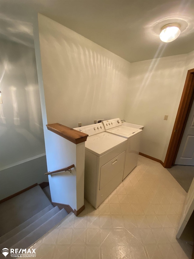 clothes washing area with light flooring, separate washer and dryer, and baseboards