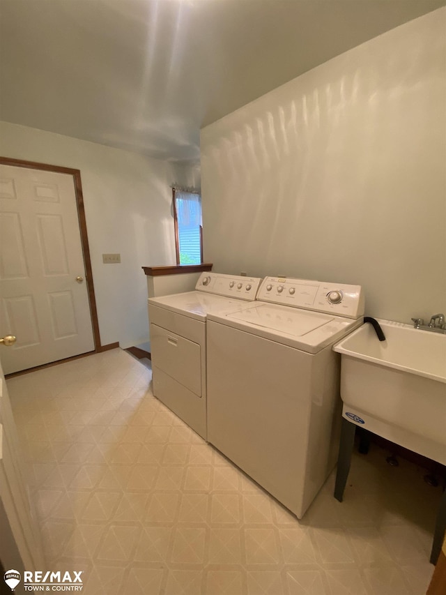 clothes washing area with washing machine and clothes dryer, light floors, and a sink