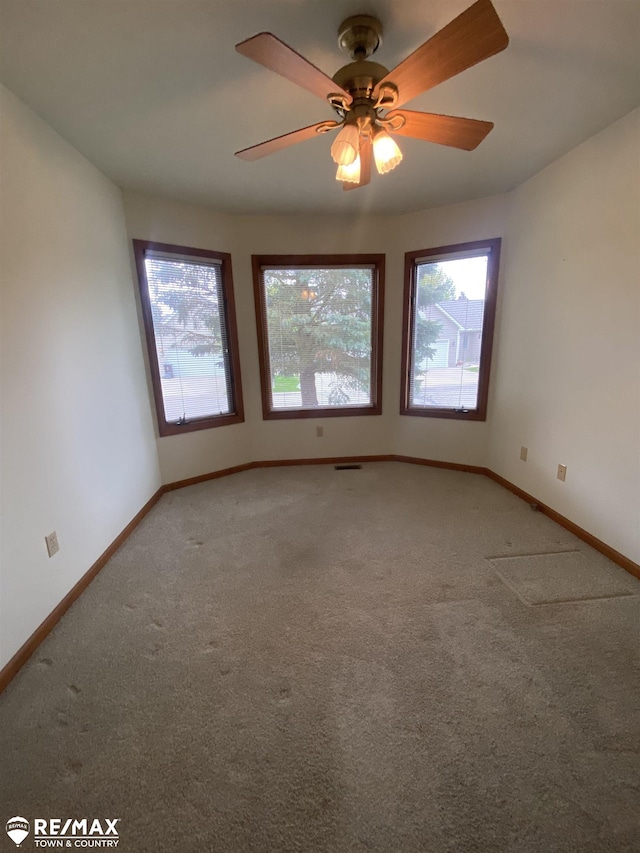spare room featuring light colored carpet, baseboards, and a ceiling fan