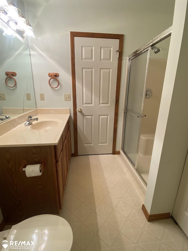 bathroom featuring tile patterned floors, a stall shower, vanity, baseboards, and toilet