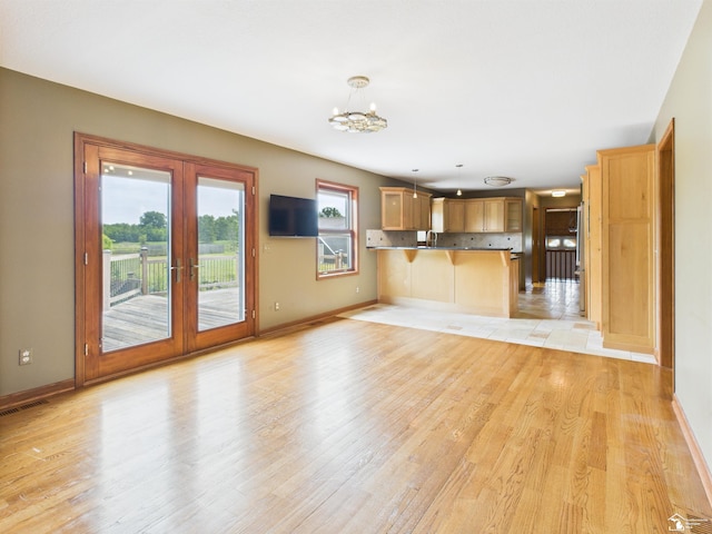 5015 Piehl Rd, Ottawa Lake, MI 49267 - unfurnished living room featuring french doors, light wood-style floors, and a chandelier
