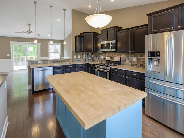 kitchen featuring stainless steel appliances, butcher block countertops, a sink, a ceiling fan, and dark wood-type flooring