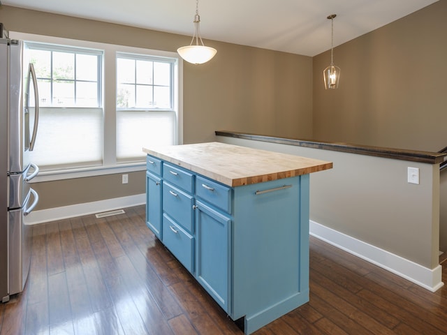 kitchen featuring blue cabinets, butcher block countertops, freestanding refrigerator, baseboards, and a center island