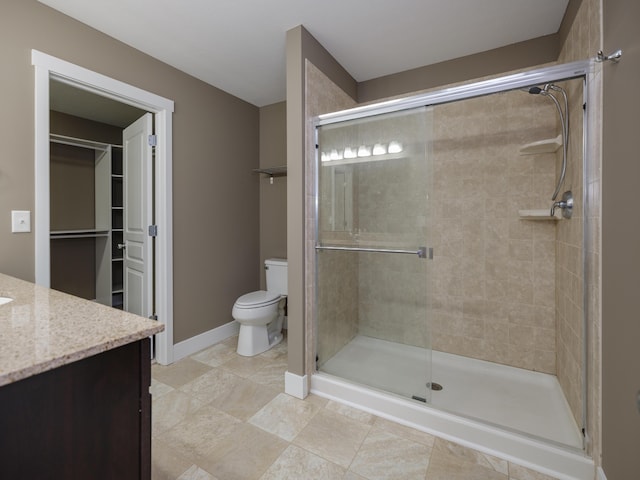 full bath with a shower stall, toilet, vanity, a walk in closet, and baseboards