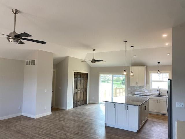 9745 W Michigan Ave, Grass Lake, MI 49240 - kitchen featuring a ceiling fan, open floor plan, white cabinets, baseboards, and wood finished floors