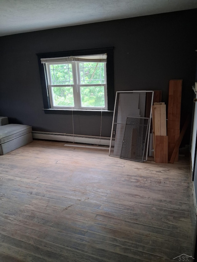 908 Lansing Ave, Jackson, MI 49202 - unfurnished living room with wood finished floors and baseboard heating