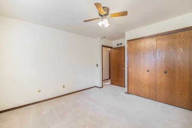 unfurnished bedroom with light carpet, a closet, a ceiling fan, and baseboards